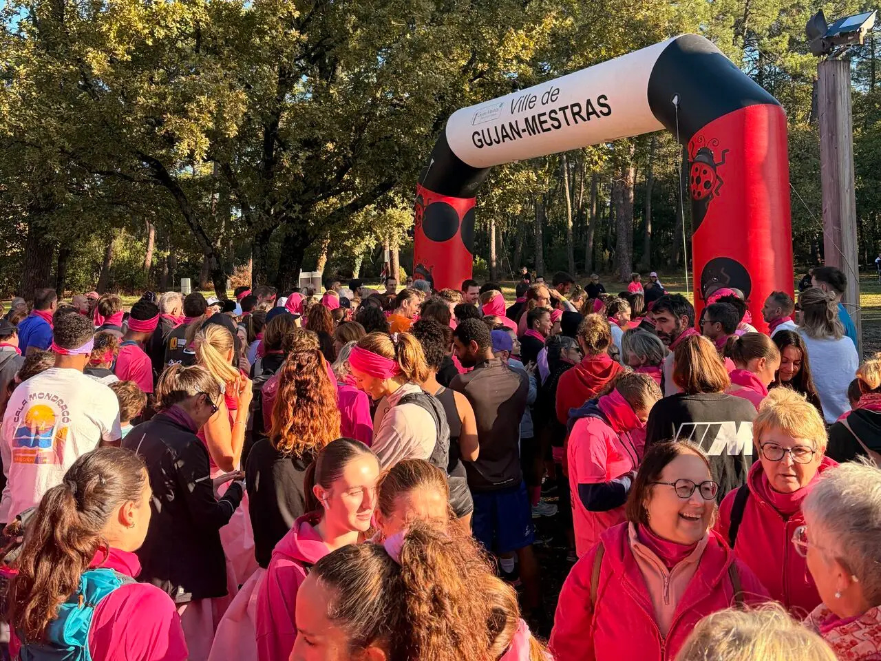 Une foule de participants vêtus de rose rassemblée sous l’arche de départ de la Ville de Gujan-Mestras, pour la course et la marche Octobre Rose