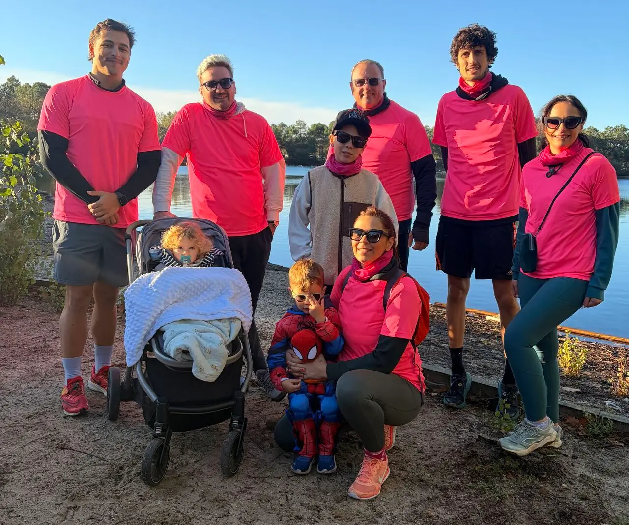 Des collaborateurs de CEO Car Caring et de MoveMyFleet en tee-shirt rose, entourés de leurs enfants, au bord d’un plan d’eau